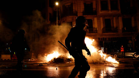 Police officers stand in front of burning garbage containers as Catalan pro-independence activist protest in Barcelona, Spain, on October 1, 2020. © Albert Gea / Reuters.
