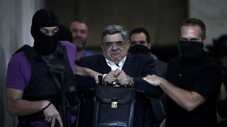 FILE PHOTO: Nikos Michaloliakos is escorted by masked police officers