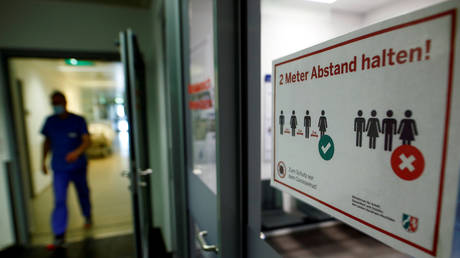 FILE PHOTO: A hospital worker walks past a sign reading "Keep two meters distance" on a door to an intensive care unit in Eschweiler, Germany.