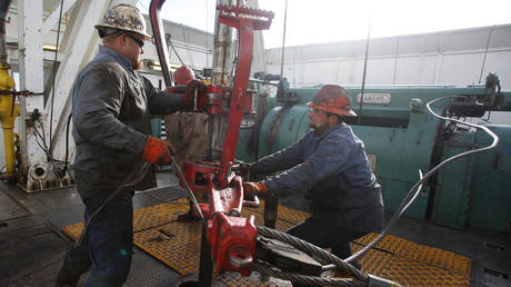 Roughnecks wrestle pipe on a True Company oil drilling rig outside Watford, North Dakota