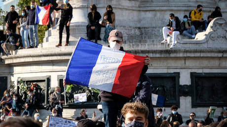 A protester holding a French flag with 'Freedom of Speech' written on it during the tribute.