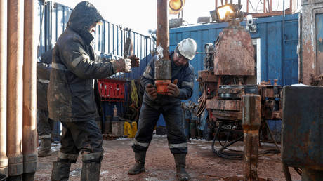 Drilling crew members move a pipe while working at an oil rig in the Yarakta Oil Field in Irkutsk Region, Russia