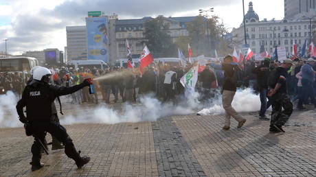 A policeman sprays demonstrators with tear gas during anti lockdown protest Warsaw, Poland. October 24, 2020. © Reuters / Agencja Gazeta / Kuba Atys