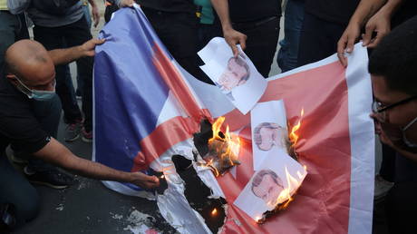 Iraqi people burn a French flag during a protest against the publications of a cartoon of Prophet Mohammad in France and French President Emmanuel Macron's comments, outside the French embassy in Baghdad, Iraq, October 26, 2020