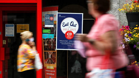 People walk past a take-out restaurant with an "Eat out to help out" poster in Luton, Britain.