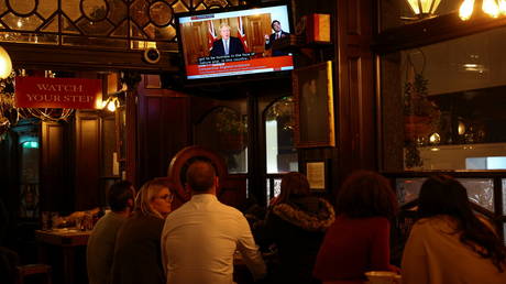 People watch Britain's Prime Minister Boris Johnson announce new lockdown measures inside a pub in Westminster, London, Britain, October 31, 2020. © Henry Nicholls / Reuters