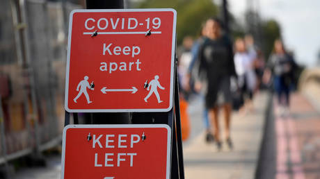 Pedestrians walk near public health signs in London, Britain, (FILE PHOTO) ©  REUTERS/Toby Melville/File Photo