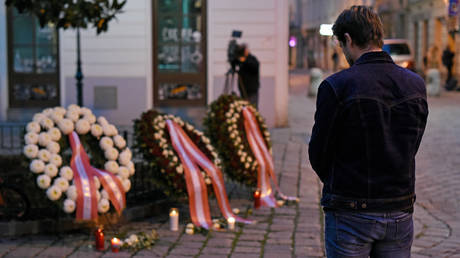 A pedestrian prays at the wreaths laid by the Austrian government at a crime scene in the city center the day after a deadly shooting spree on November 03, 2020 in Vienna, Germany