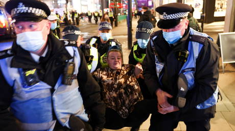 A woman is detained by police officers as protestors from the Million Mask March and anti lockdown protestors demonstrate, amid the coronavirus (COVID-19) outbreak in London, Britain November 5, 2020.