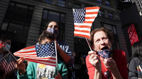 People react as media announce that Democratic US presidential nominee Joe Biden has won the US presidential election, on Times Square in NYC.