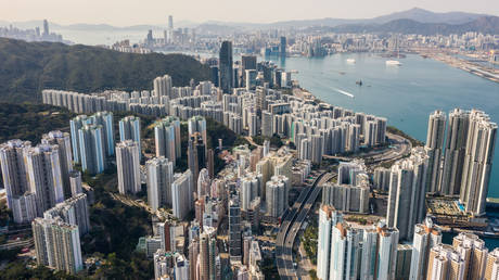 FILE PHOTO An aerial view shows residential and commercial buildings on Hong Kong island (foreground and top L) and Kowloon (top C and R), either side of Victoria Harbour, on February 17, 2020. © AFP / Anthony WALLACE