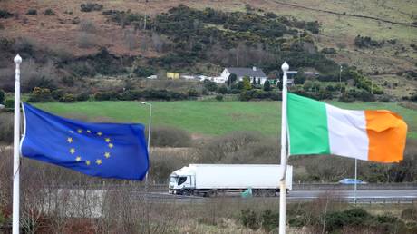 FILE PHOTO: The European Union flag and national flag of Ireland on the border road between Dundalk, Ireland, and Newry in Northern Ireland. February 2020. ©  AFP / Paul Faith