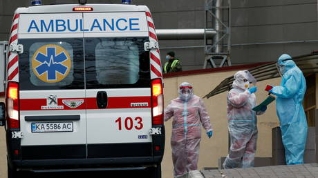 Medical specialists wearing protective gear stand next to an ambulance outside a hospital for patients infected with the coronavirus disease in Kyiv, Ukraine November 9, 2020. © REUTERS/Gleb Garanich