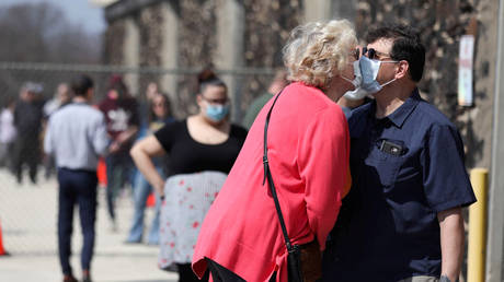 FILE PHOTO: Wisconsin residents kiss while wearing face masks as they wait in line outside a polling station, in Milwaukee, Wisconsin.