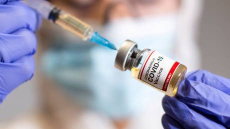 FILE PHOTO: A woman holds a small bottle labeled with a "Coronavirus COVID-19 Vaccine" sticker and a medical syringe in this illustration taken, October 30, 2020
