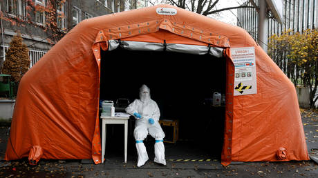 FILE PHOTO. A health worker in protective suit waits for people at a test center in Warsaw, Poland.