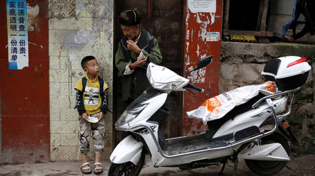 A child stands next to an old man on the street in Ganluo county of Liangshan Yi Autonomous Prefecture, Sichuan province, China