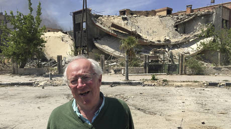 Veteran British journalist Robert Fisk stands in front of a damaged building in the Damascus suburb of Douma, April 16, 2018. © AP Photo/Bassem Mroue