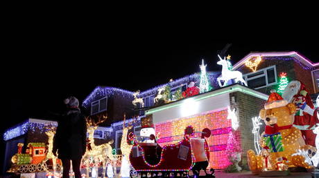 A person looks at a house displaying Christmas lights in Hemel Hempstead, UK