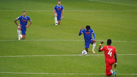 Players at Colchester United take a knee before a League Two match. © PA Images via Getty Images