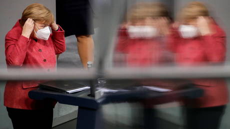 German Chancellor Angela Merkel puts on her face mask as she attends a session of Bundestag in Berlin, Germany on December 9, 2020.