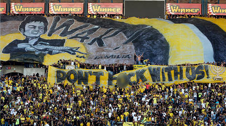 In this file photo taken on August 17, 2016 Beitar Jerusalem fans hold up banners prior to the UEFA Europa League play-off football match between Beitar Jerusalem and AS Saint-Etienne, at the Itztadion Teddy Stadium in Jerusalem.  © AFP / AHMAD GHARABLI