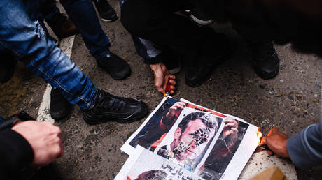 FILE PHOTO: Demonstrators opposing the publication in France of cartoons of the Prophet Mohammad set fire to images depicting French President Emmanuel Macron during a protest outside the French Embassy in London, England, on October 30, 2020