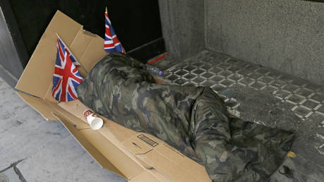 FILE PHOTO: A homeless person lays on cardboard decorated with Union Flags in central London.