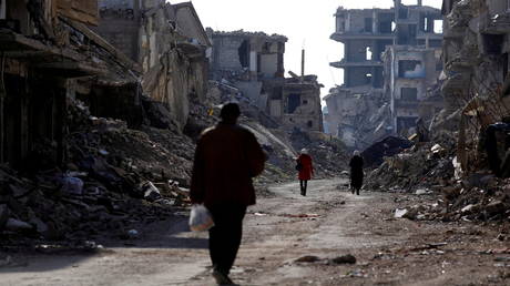 People walk past damaged buildings at the Yarmouk refugee camp on the southern outskirts of Damascus