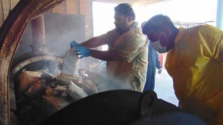 Marshall Islands Police emptying one-kilo packages of cocaine into an incinerator. © Giff JOHNSON / AFP