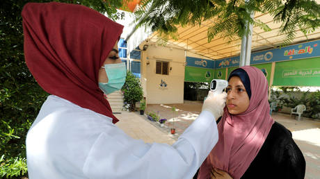 A Palestinian healthcare worker checks resident's body temperature amid a coronavirus outbreak in Gaza. © Reuters / Mohammed Salem