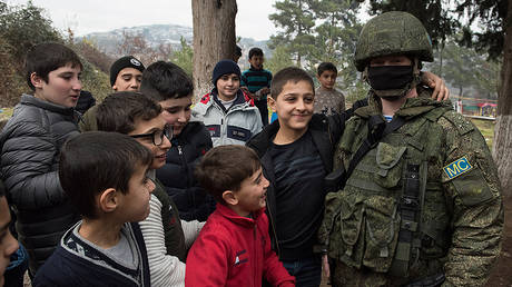 A representative of Russian peacekeepers poses with schoolchildren in the village of Chartar, the self-proclaimed Nagorno-Karabakh Republic. © Sputnik / Valeriy Melnikov