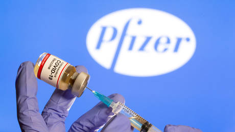 FILE PHOTO: A woman holds a small bottle labeled with a "Coronavirus COVID-19 Vaccine" sticker and a medical syringe in front of displayed Pfizer logo in this illustration taken, October 30, 2020.