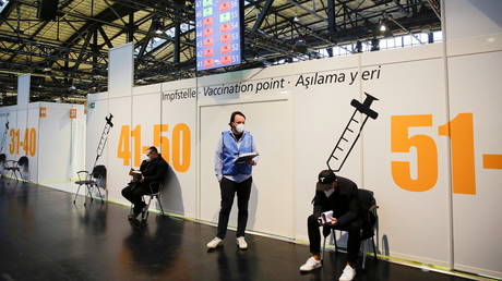 FILE PHOTO: Two men wait for their vaccine against the coronavirus disease (COVID-19) at the Treptow Arena vaccination center in Berlin, Germany, on December 27, 2020.