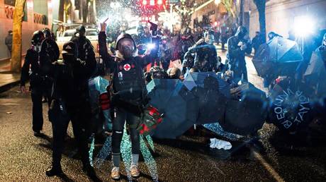 A demonstrator is shown gesturing toward police after a riot was declared Thursday night in Portland.