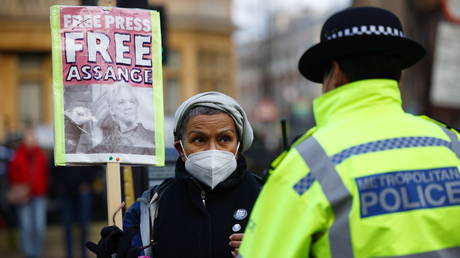 A woman holding a placard looks at a police officer outside at the Westminster Magistrates Court ahead of a hearing as Assange's lawyers seek bail for their client in London, Britain January 6, 2021.