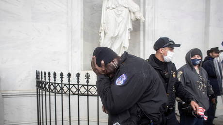 FILE PHOTO: A member of the Capitol police covers his face as pro-Trump protesters storm the US Capitol in Washington, DC, US, January 6, 2021