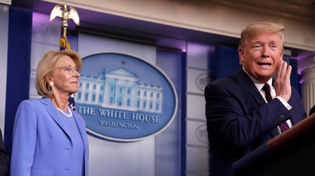 FILE PHOTO: President Donald Trump addresses press briefing as Education Secretary Betsy DeVos looks on at the White House in Washington, DC.