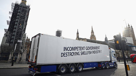 A lorry with a sign in protest against post-Brexit bureaucracy that hinders exports to the European Union, drives at the Parliament Square in London, Britain, January 18, 2021. © REUTERS/Hannah McKay