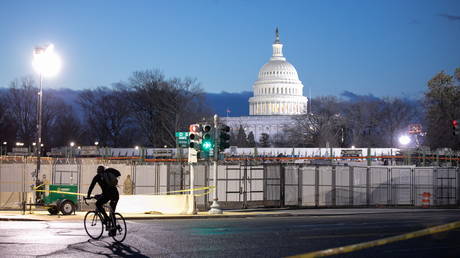 A cyclist passes the U.S Capitol secured with additional fencing and barriers before sunrise on President-elect Joe Biden's Inauguration Day in Washington, U.S., January 20, 2021.