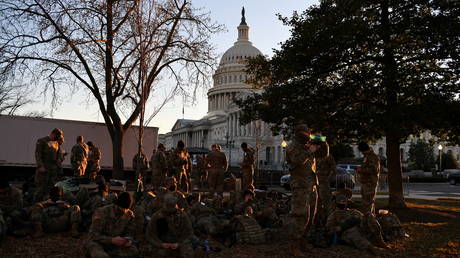 National Guard troops rest on a yard in front of the US Capitol