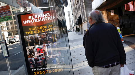 A local resident looks at an FBI billboard featuring participants in the Capitol Hill riot, in Washington, DC, January 13, 2021 © Reuters / Carlos Barria