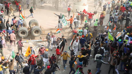 Protesters cheer after overturning a trailer during a tractor rally to protest against farm laws near New Delhi on Tuesday. © REUTERS/Anushree Fadnavis