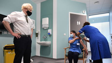 Britain's Prime Minister Boris Johnson looks on as Jennifer Dumasi receives the Oxford University/AstraZeneca COVID-19 vaccine during his visit at the Chase Farm Hospital, in north London, Britain January 4, 2021.