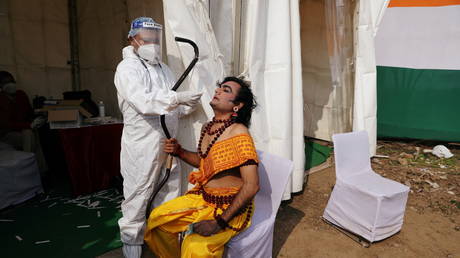 A healthcare worker wearing personal protective equipment (PPE) collects a swab sample from an artist in New Delhi, India (FILE PHOTO) © REUTERS/Anushree Fadnavis