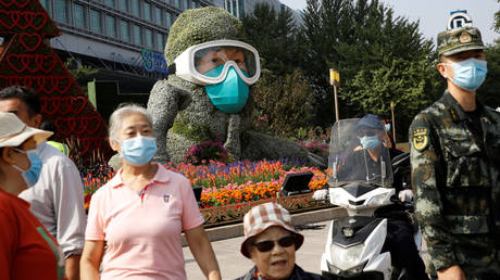 FILE PHOTO. People walk past a floral installation featuring a medical worker on Changan Avenue in Beijing. ©REUTERS / Tingshu Wang