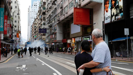 A couple hugs each other as police fire tear gas into the crowds to disperse anti-national security law protesters during a march at the anniversary of Hong Kong's handover to China from Britain in Hong Kong, China (FILE PHOTO) © REUTERS/Tyrone Siu