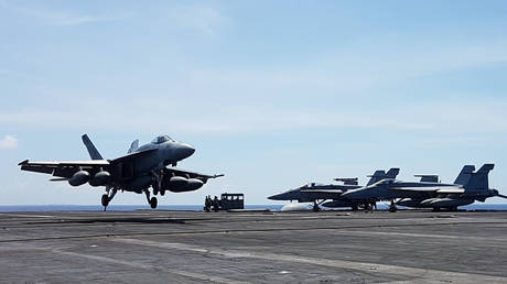 FILE PHOTO: An F-18 fighter, on patrol, lands on the deck of the USS Theodore Roosevelt, transiting the South China Sea April 10, 2018