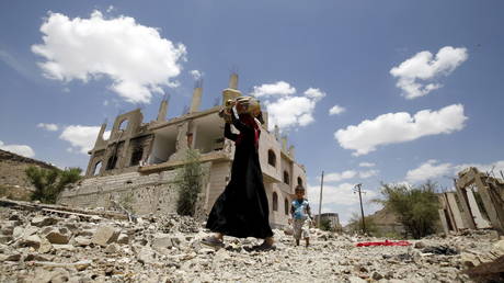 FILE PHOTO: A woman and a boy walk past the ruins of buildings destroyed in Saudi-led air strikes in Yemen's capital Sanaa, September 13, 2015