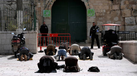 Muslim worshippers pray near a closed gate of the compound housing Al-Aqsa mosque in Jerusalem's Old City after prayers at the compound were be suspended to prevent the spread of the coronavirus. © Reuters / Ammar Awad